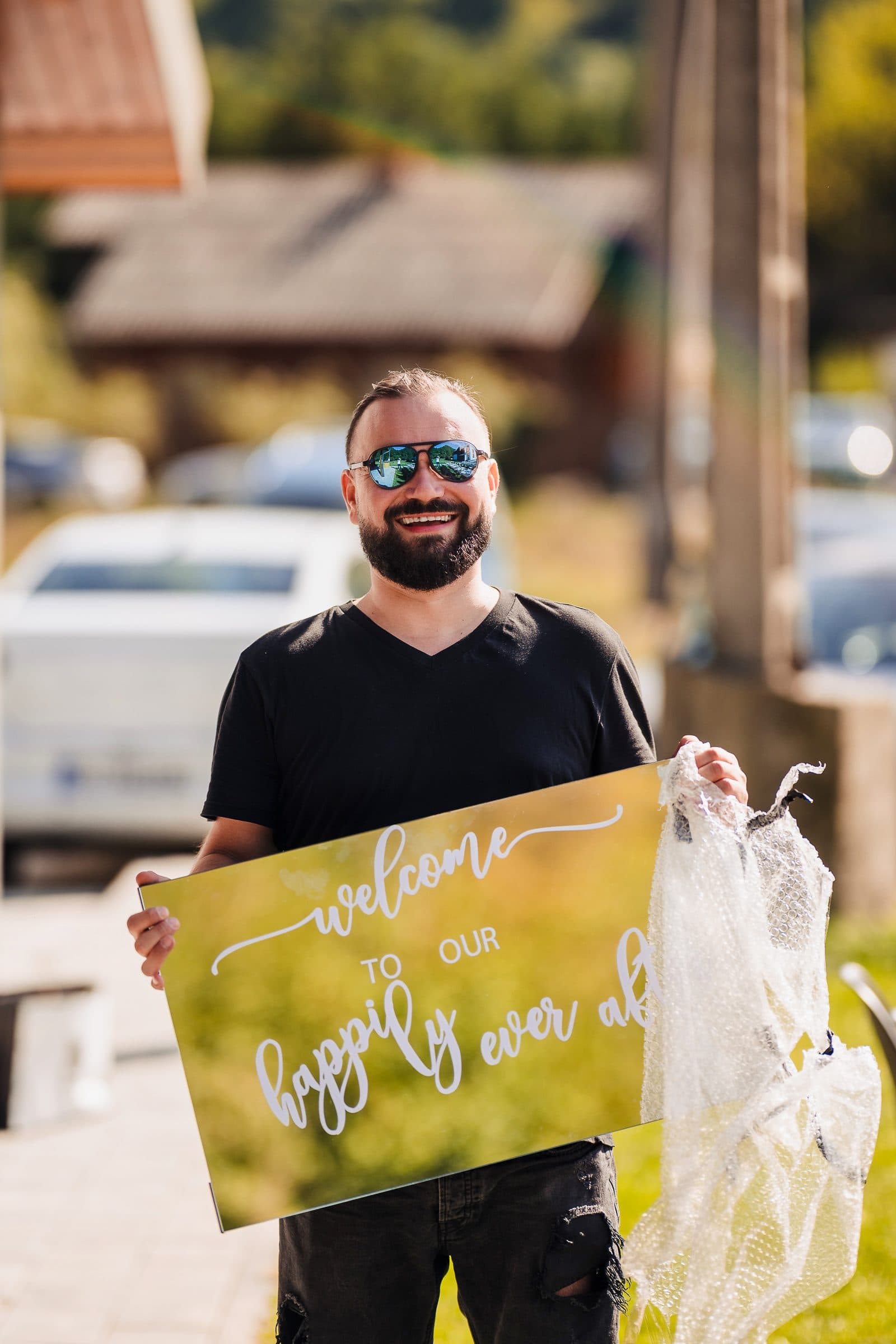 A friend in sunglasses holds a welcome sign at the entrance