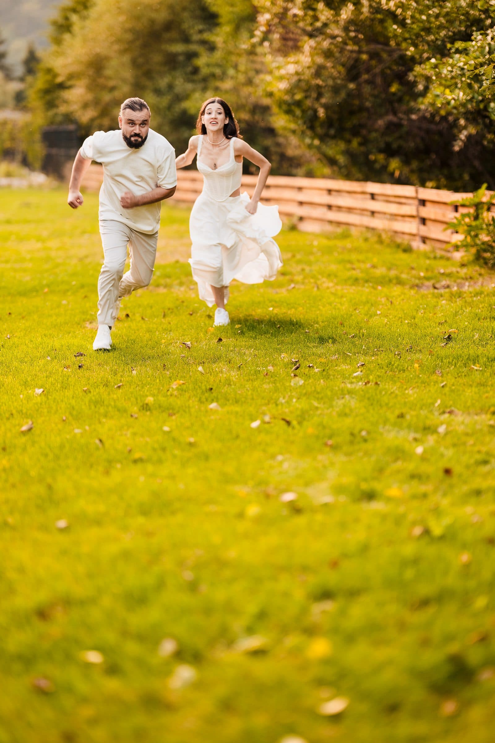 The couple races each other barefoot across the grass, laughing