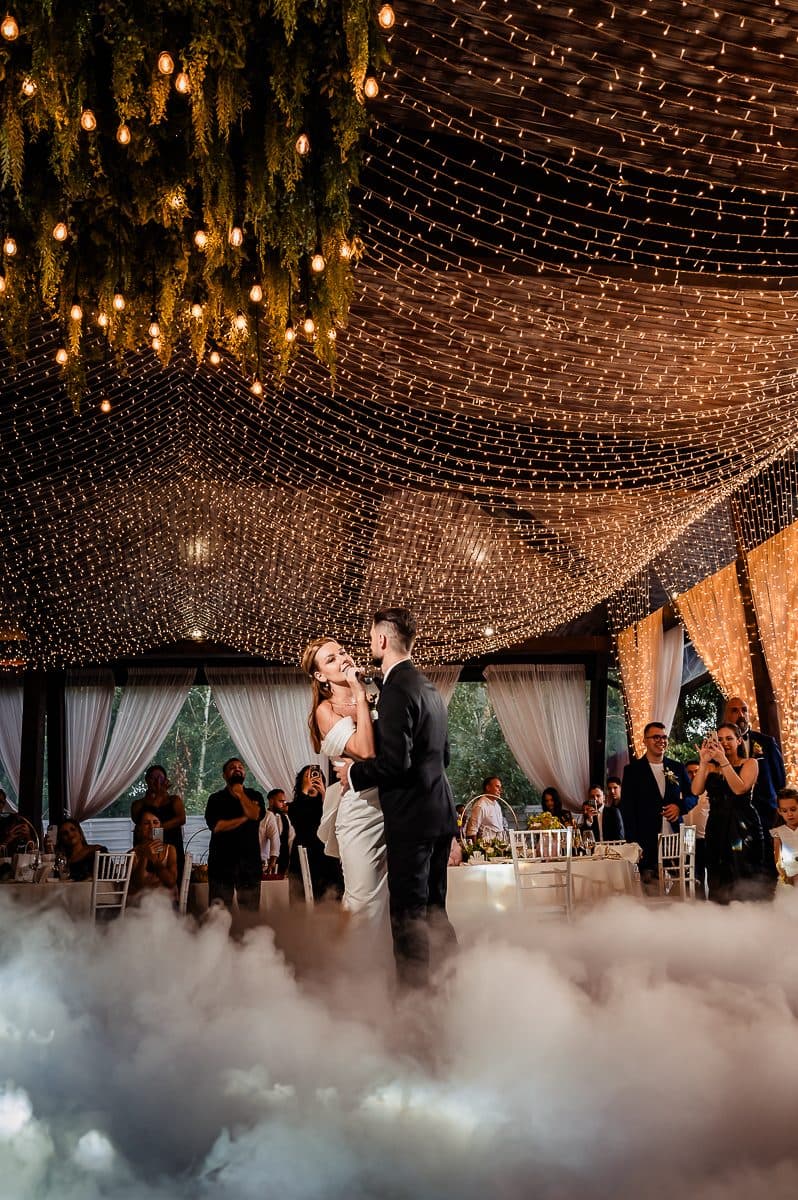 The couple dances through the fog while guests watch from their tables