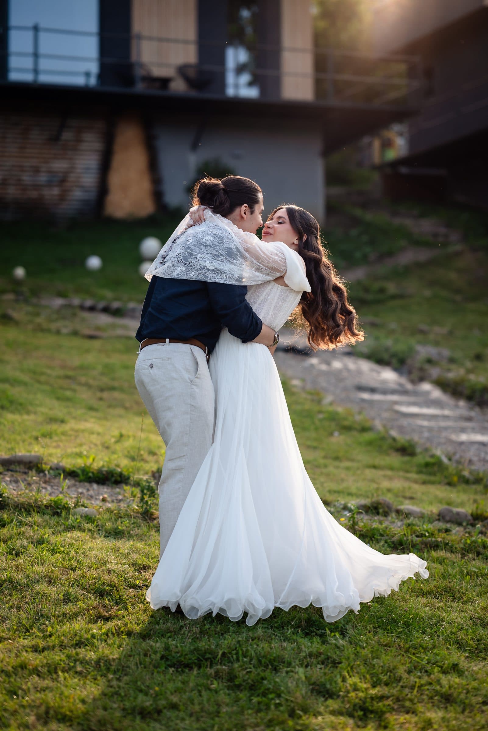 The couple holds each other on the lawn, the bride's dress sweeping the grass