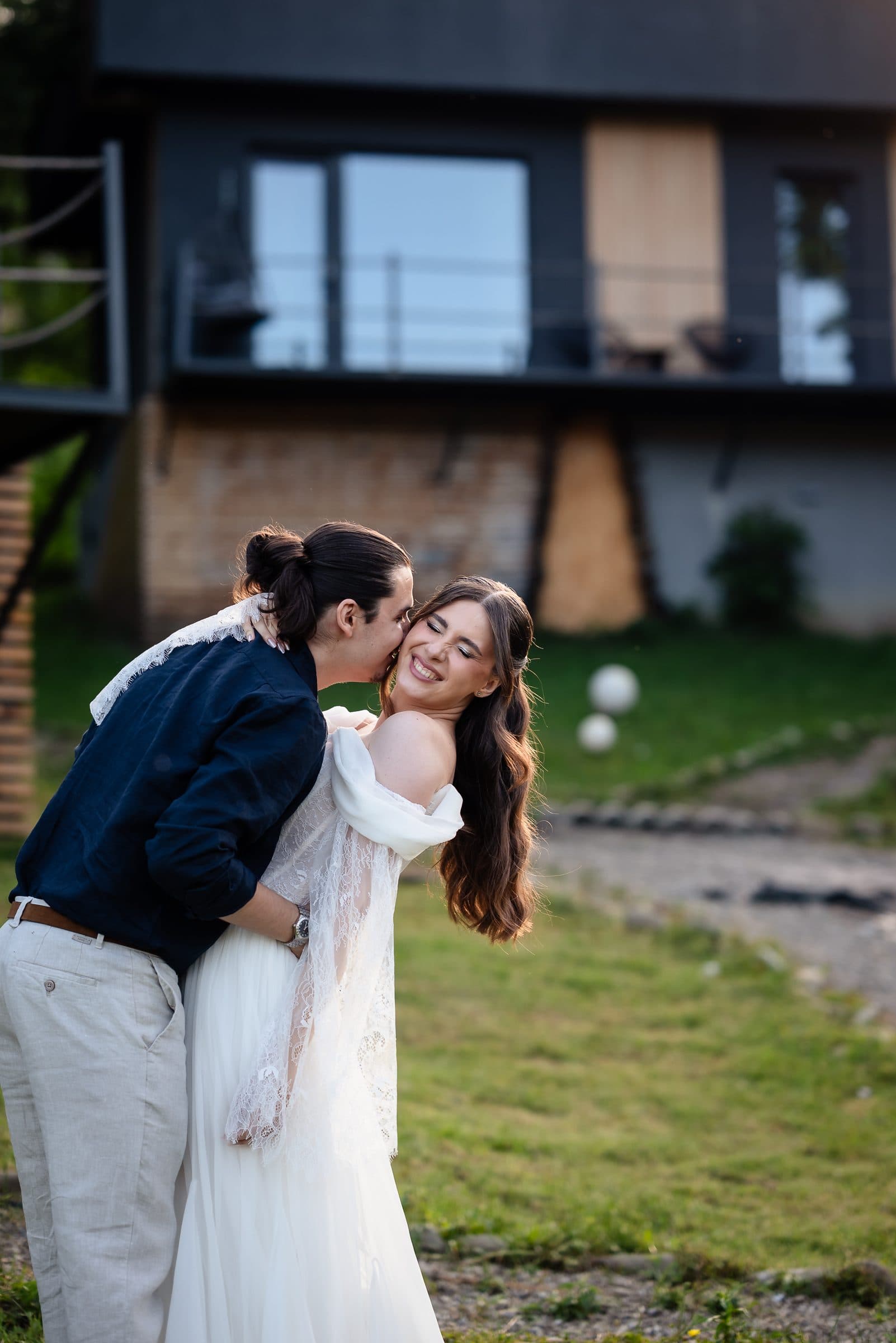 The groom kisses the bride's cheek; she laughs