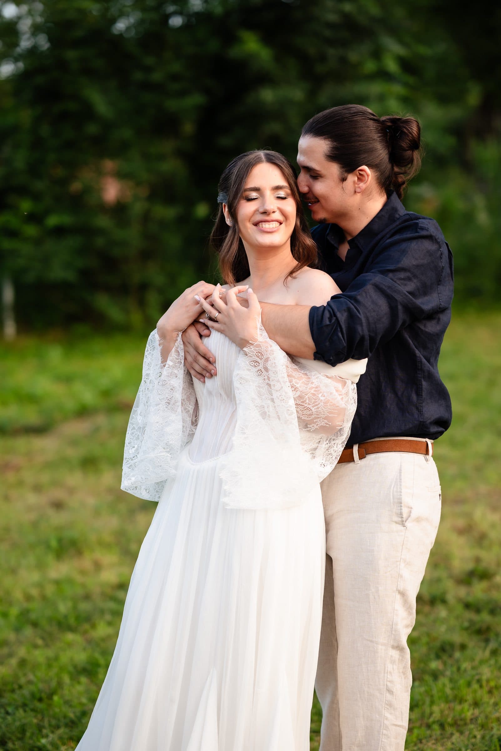 The groom rests his face against the bride's as she smiles, eyes closed