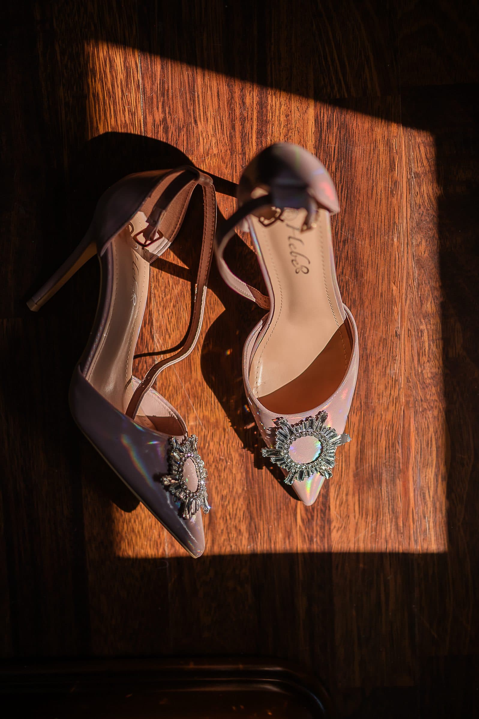 The bride's shoes in a square of window light on a wooden floor