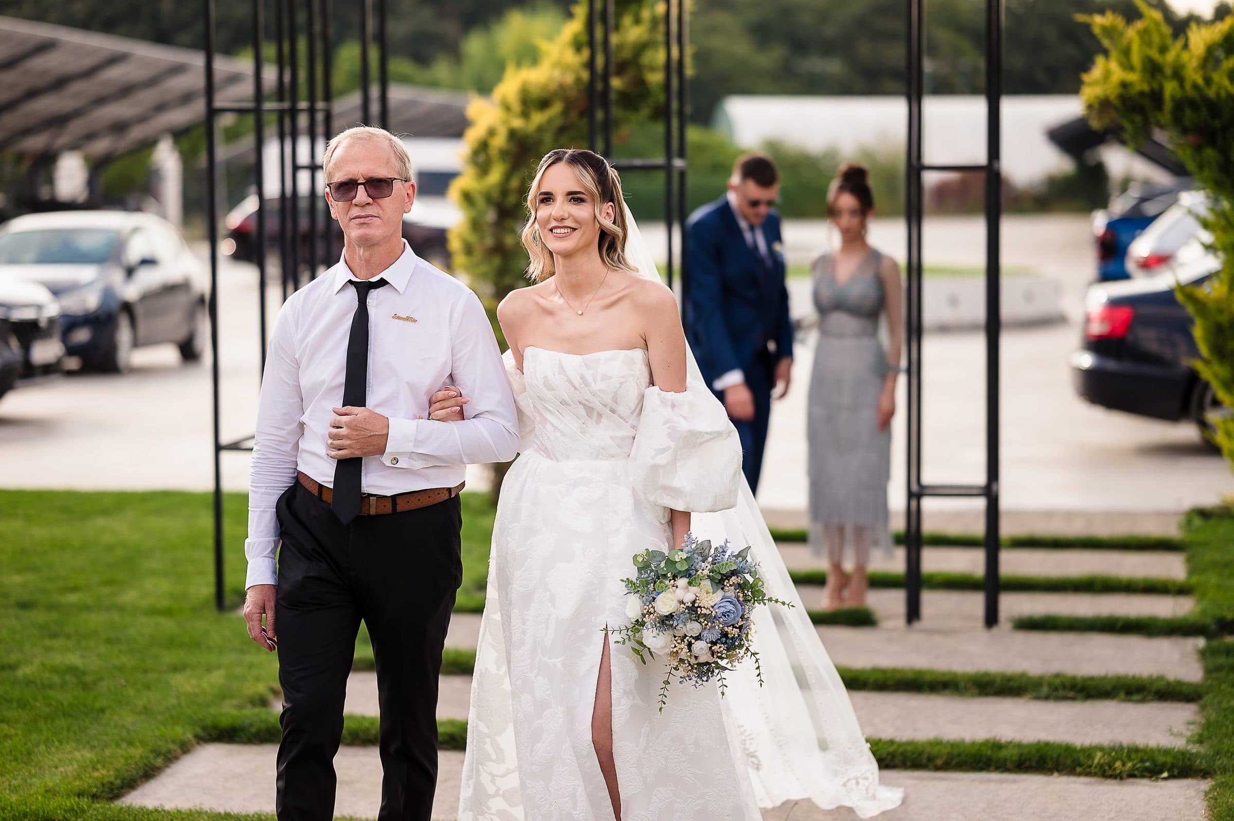 The bride walks to the ceremony on her father's arm