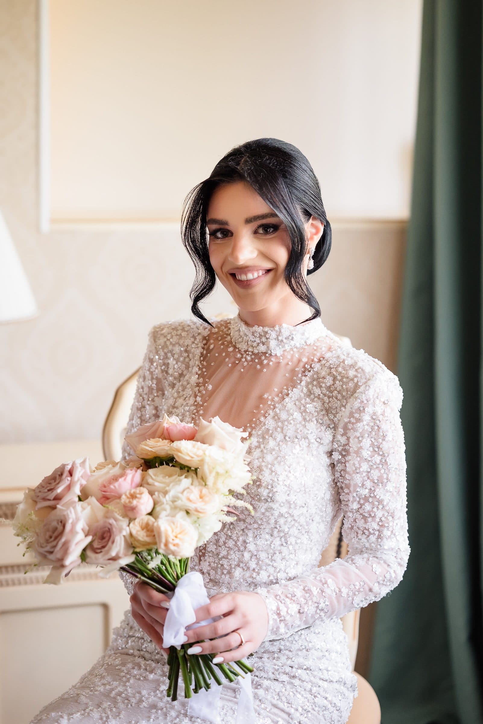 Close portrait of the bride smiling, holding a bouquet of blush roses