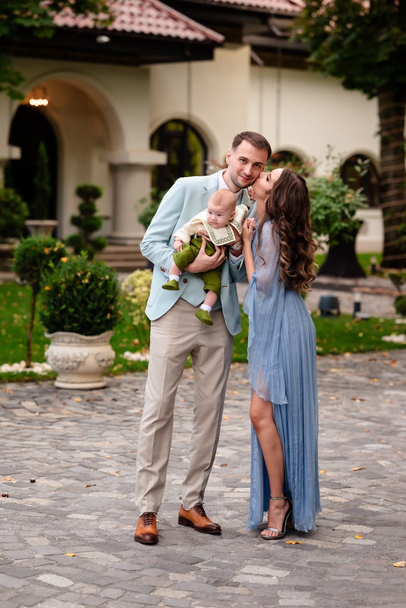 The mother kisses the father's cheek as he holds the baby