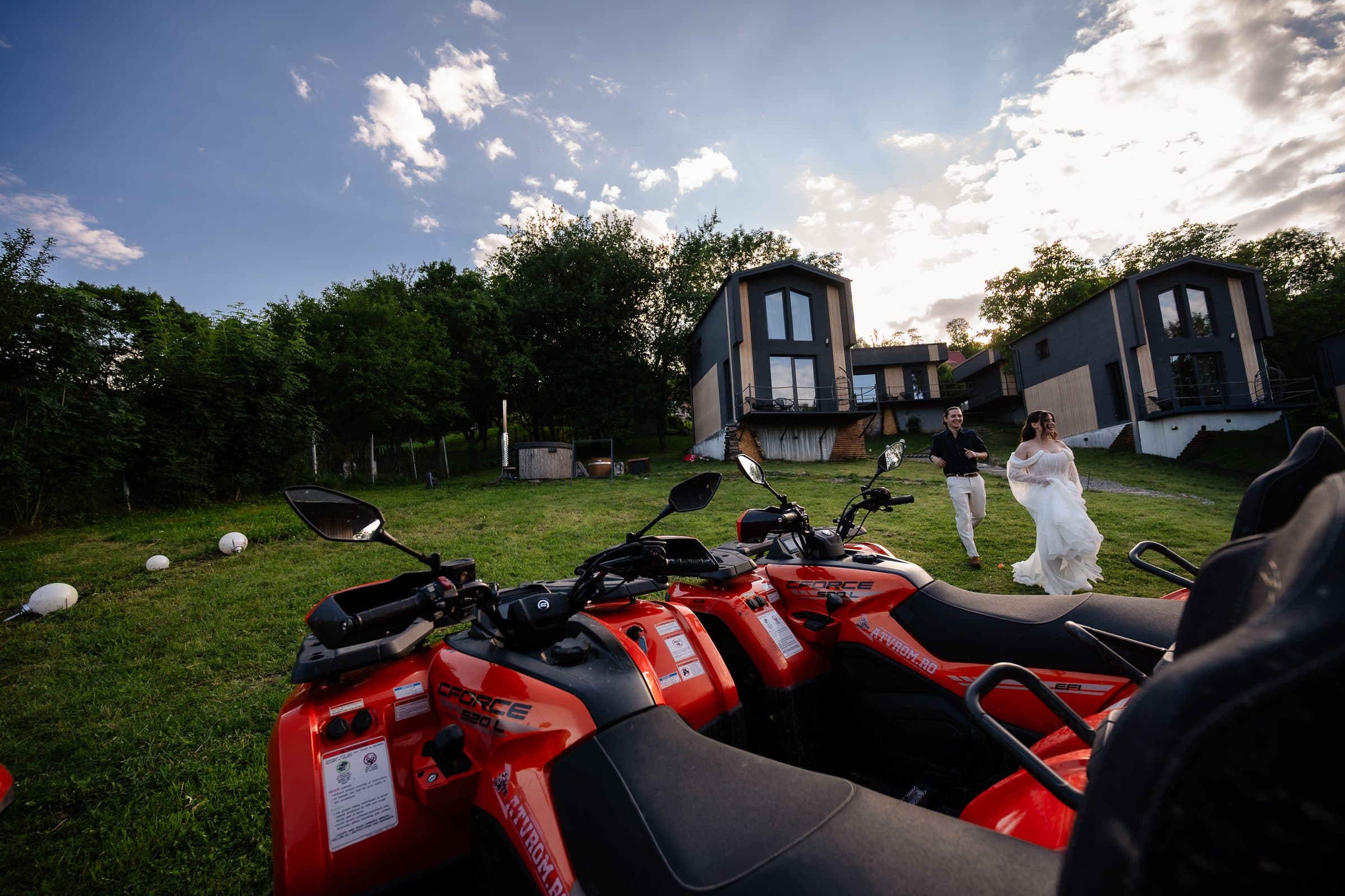 Wide view: red quad bikes in the foreground, the couple small on the lawn behind